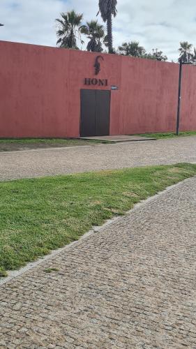 a red wall with a door with the word lion on it at Apartamento 50mt Praia Póvoa Varzim in Póvoa de Varzim