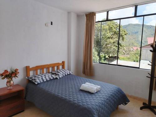 a bedroom with a bed and a large window at Casa Hospedaje Don Augusto Oxapampa in Oxapampa