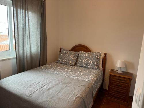 a small bedroom with a bed with a window at Cabo Sardão Guest House in Odemira