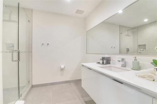 a white bathroom with two sinks and a shower at Rooftop Pool - Hot Tub - Gym - Near Beach in Hollywood