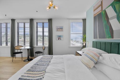 a bedroom with a bed and a table and windows at Norblad Hotel in Astoria, Oregon