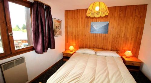 1 Schlafzimmer mit einem Bett, 2 Fenstern und einem Kronleuchter in der Unterkunft Résidence Le Centre - 2 Pièces pour 6 Personnes 193303 in Champagny-en-Vanoise