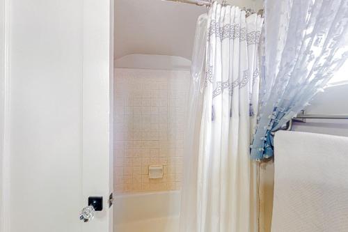 a shower with a white shower curtain next to a tub at Make Mine Mesa - Unit A in Mesa