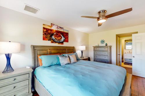 um quarto com uma cama azul e uma ventoinha de tecto em Valley of the Sun em Phoenix