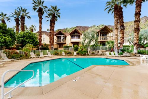 a swimming pool in front of a house with palm trees at Mountain Cove Modern in Indian Wells