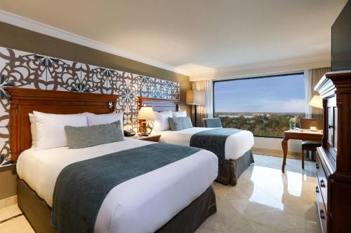 two beds in a hotel room with a large window at Villahermosa Marriott Hotel in Villahermosa