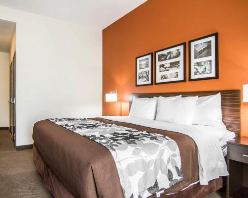 a large bed in a hotel room with orange walls at Sleep Inn Lufkin in Lufkin