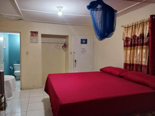 a bedroom with a large bed with a red blanket at Tina's Guest House in Ocho Rios