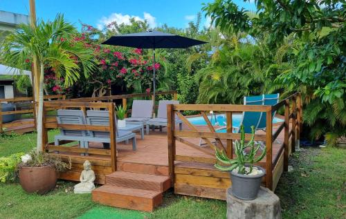 une terrasse en bois avec des chaises et un parasol dans l'établissement La Villa Rainbow & ses 2 Kabanes, à Sainte-Anne