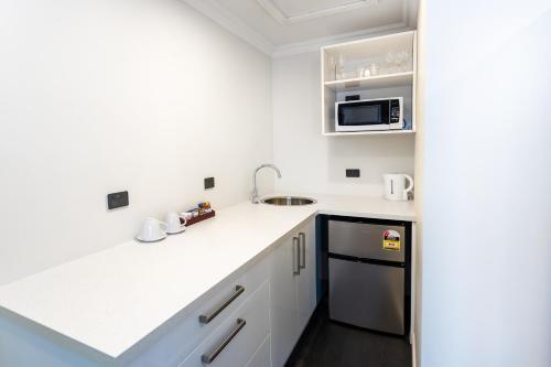 a white kitchen with a sink and a microwave at Superior Dunedin Apartments in Dunedin