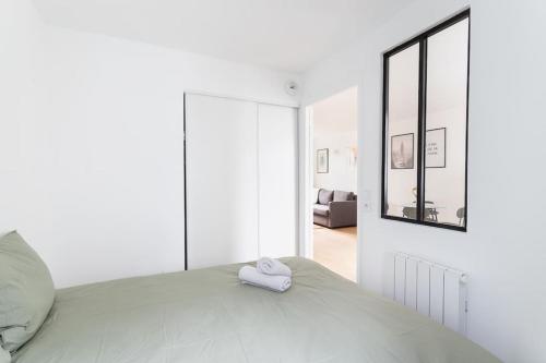 a white bedroom with a bed and a mirror at Lille - Bel Appartement Cosy et Lumineux in Lille