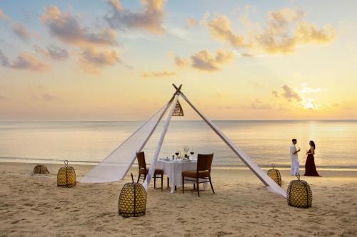 a dinner table on the beach at sunset at The Ritz-Carlton, Langkawi in Pantai Kok