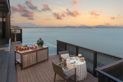 a deck with a table and chairs with a view of the water at The Ritz-Carlton, Langkawi in Pantai Kok