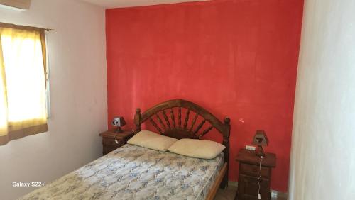 a bedroom with a bed and a red wall at Cabañas La Dorita in Paso de la Patria