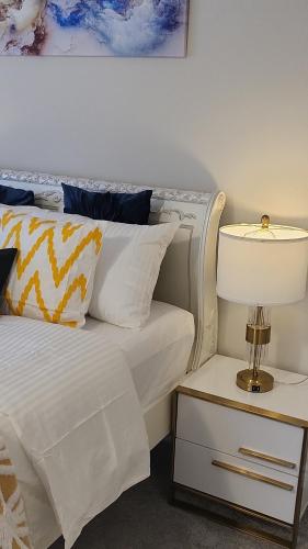 una cama con sábanas blancas y una lámpara en una mesita de noche en PLEASANT ROOM, en Milton