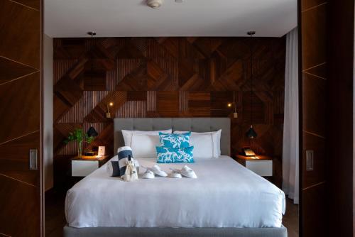 a bedroom with a large white bed with blue pillows at The Fives Downtown Hotel & Residences, Curio Collection by Hilton in Playa del Carmen