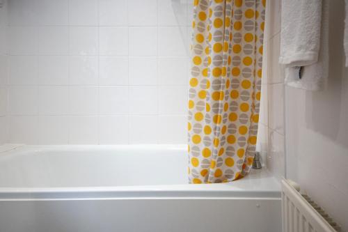 a bathroom with a shower curtain with a tub at Thornton House Apartments, Cambridge - FREE On-site Parking in Girton