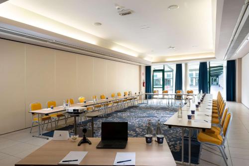 a conference room with tables and chairs and a laptop at Doubletree by Hilton Milan Malpensa Solbiate Olona in Solbiate Olona