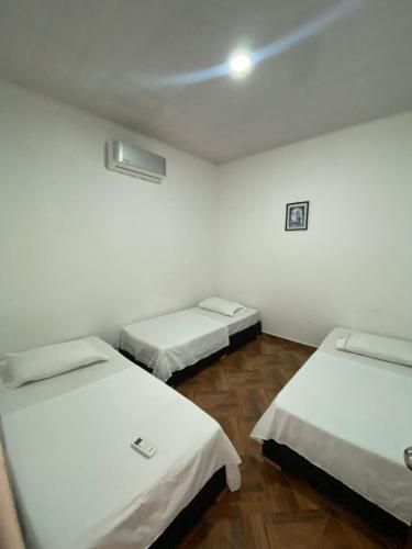 3 camas en una habitación con paredes blancas y suelo de madera en Apartamentos Amoblados Napoles en Doradal