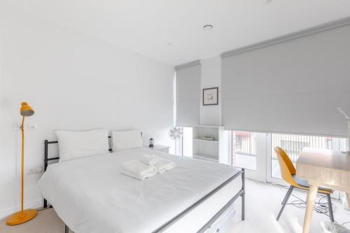 ロンドンにあるStylish 2BD Oasis wBalcony South East London!の白いベッドルーム(ベッド1台、テーブル、椅子付)