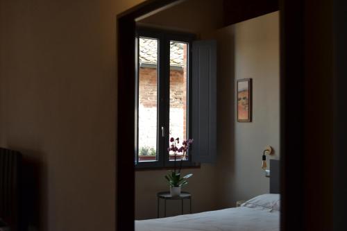 a bedroom with a bed and a window with flowers at Pagum Place in Torrita di Siena