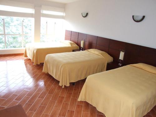 a hotel room with three beds with yellow blankets at Hotel El Castillo Chinauta in Chinauta