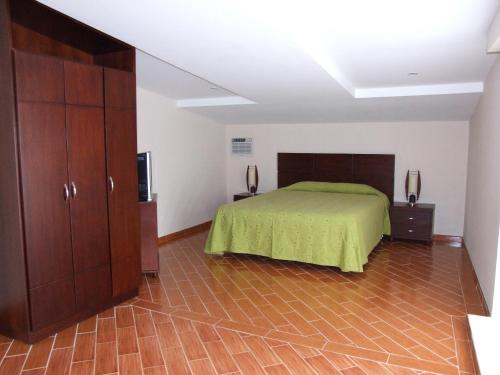 a bedroom with a bed with a green bedspread at Hotel El Castillo Chinauta in Chinauta