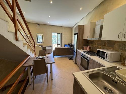 uma cozinha com um lavatório, uma mesa e um micro-ondas em The Nest Siekel Townhouse em Għajn il-Kbira