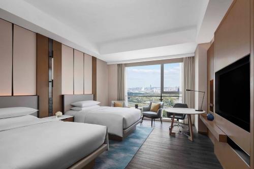 a hotel room with two beds and a flat screen tv at Jiaxing Marriott Hotel in Jiaxing