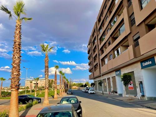 eine Straße mit Autos neben einem Gebäude mit Palmen in der Unterkunft Cosy Apartment Menara Garden in Marrakesch