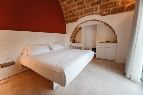 een slaapkamer met een wit bed in een bakstenen muur bij La Vacia Boutique Country Resort in Pulsano