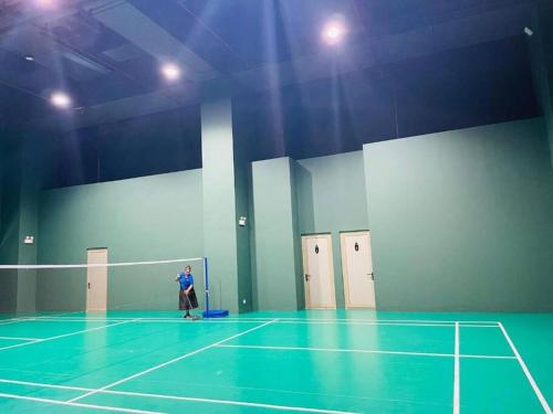 a person standing on a tennis court with a net at The Grand Luxury Apartment in Heart of Colombo (Ward Place Col 07) in Colombo