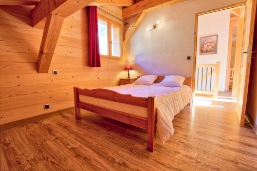 1 dormitorio con 1 cama en una cabaña de madera en Résidence Le Champ De La Caille - Chalets pour 8 Personnes 54 en Notre-Dame-de-Bellecombe