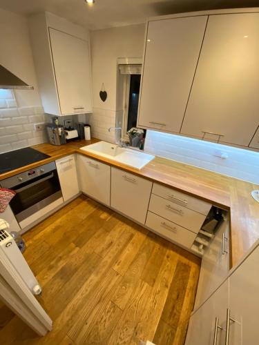 Il comprend une cuisine avec des placards blancs et du parquet. dans l'établissement Broxbourne apartment (2 bed), à Broxbourne