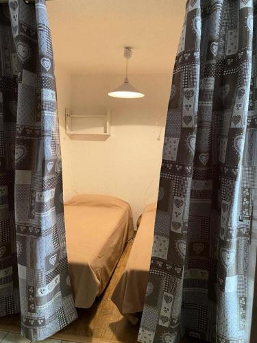 Cette chambre dispose de deux lits et de rideaux sur la fenêtre. dans l'établissement Résidence Rochechateau - Studio cabine 4 personnes 2 exposé Ouest MAE-4234, à Valloire