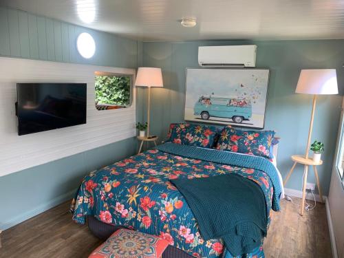 a bedroom with a bed and a flat screen tv at Mornington Peninsula Retro Caravans in Rye