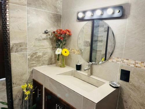 a bathroom with a sink with a mirror and flowers at Hostel Gautamas Guest rooms in Tepoztlán