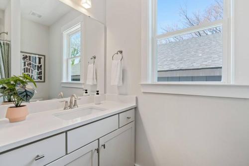 een witte badkamer met een wastafel en een raam bij 3bd Contemporary in Raleigh: 5mins to Downtown in Raleigh