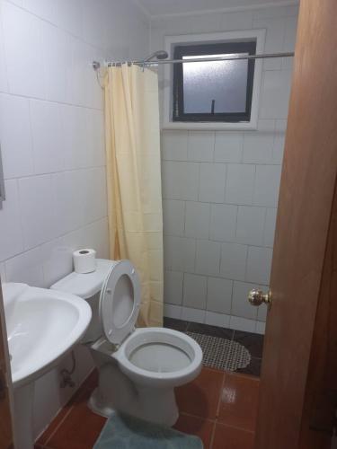 a bathroom with a toilet and a sink and a window at Casa Cardenal in Castro