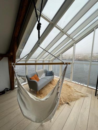 a hammock in a room with a view of the water at Tórhús in Miðvágur