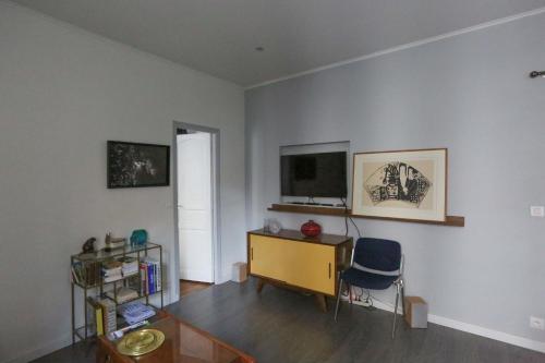 Apartment at the gateway to Paris في فينسين: غرفة معيشة مع مكتب وتلفزيون على الحائط