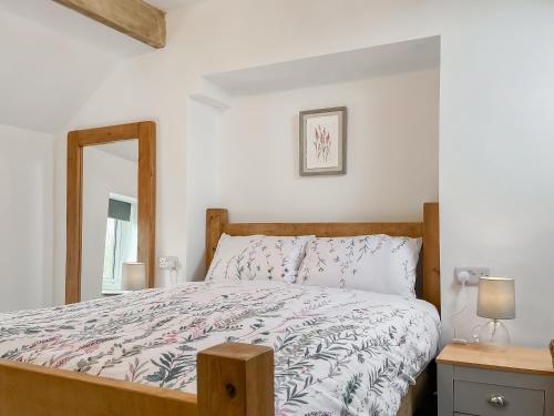 a bedroom with a bed with a wooden frame and a mirror at Jasmine Cottage in Elton