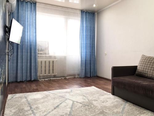 a living room with a couch and a large window at Уютные апартаменты рядом с Ситицентром in Uralsk