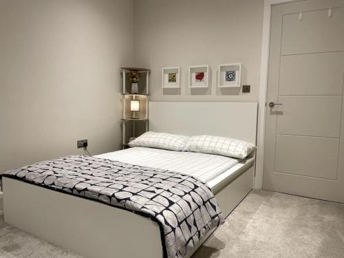 London Southgate 2bed Apartment في لندن: غرفة نوم بسرير في غرفة بيضاء