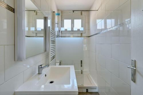 une salle de bain blanche avec un lavabo et un miroir dans l'établissement Belle Vue - T5 rénové avec balcon et parking, à Marseille