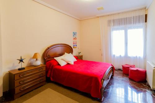 a bedroom with a red bed and a window at Villa Taala con terraza in Los Nietos