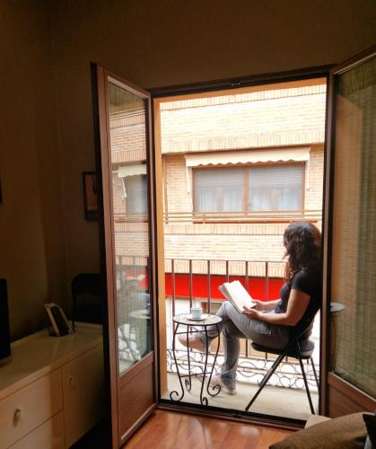 a woman sitting on a chair reading a book on a balcony at El Cervunal in Arenas de San Pedro