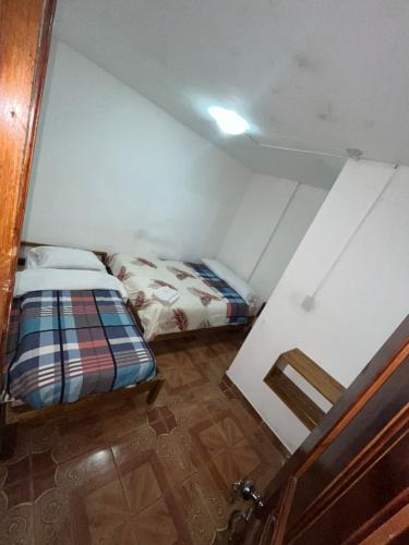 a small room with a bed and a door at Hostal Don Viche in Mindo