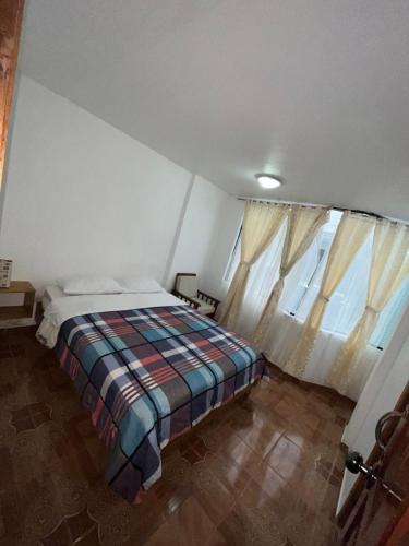 a bedroom with a bed in a room with windows at Hostal Don Viche in Mindo