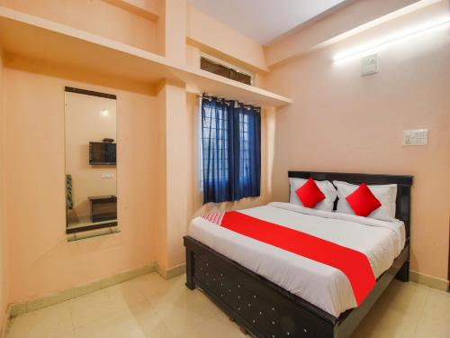 1 dormitorio con 1 cama grande con almohadas rojas en OYO R.J.international, en Pedda Ambarpet